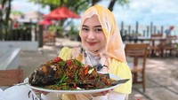 Ria Ricis juga menikmati hidangan seafood di Phuket. Ia tampak menunjukkan sebuah ikan goreng jumbo dengan Thai tea sebagai penyegarnya. (Foto: dok Instagram riaricis1795)