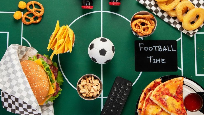 Football game watch party food and snacks on a football field. Football party. Top view.