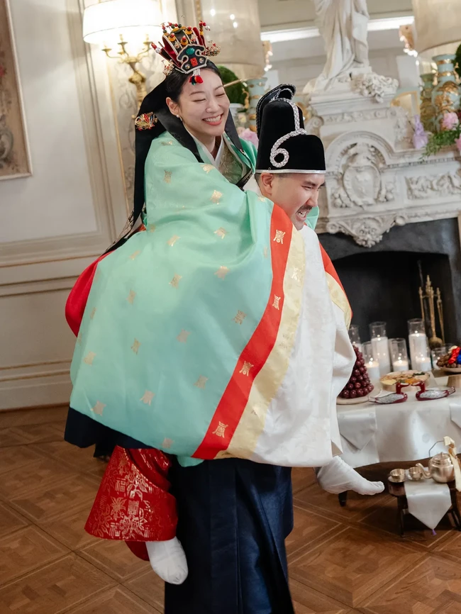 Kali ini, Chris dan Arden memakai hanbok bernuansa hijau tosca dan merah. Warna tosca menandai awal baru, pertumbuhan, serta pernikahan yang langgeng dan harmanis. Sementara rok merah yang dikenakan Arden melambangkan kegembiraan, kemakmuran, dan keberuntungan. Penampilan Arden juga dilengkapi hiasan kepala yang disebut jokduri. Foto: dok. Vogue Weddings
