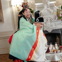 Kali ini, Chris dan Arden memakai hanbok bernuansa hijau tosca dan merah. Warna tosca menandai awal baru, pertumbuhan, serta pernikahan yang langgeng dan harmanis. Sementara rok merah yang dikenakan Arden melambangkan kegembiraan, kemakmuran, dan keberuntungan. Penampilan Arden juga dilengkapi hiasan kepala yang disebut jokduri. Foto: dok. Vogue Weddings