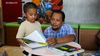Orang tua mendampingi anak membaca buku. Beragam koleksi bacaan dan ruang yang nyaman mendorong minat baca sejak usia dini.