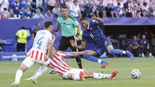 PHILADELPHIA, PENNSYLVANIA - JULY 4: Michael Olise #11 of France, left Matias Galarza #23 of Paraguay, behind referee Ilgiz Tantashev of Uzbekistan during the FIFA World Cup 2026 Round Of 16 football match between Paraguay and France at Philadelphia Stadium on July 4, 2026 in Philadelphia, Pennsylvania. (Photo by Jean Catuffe/Getty Images)