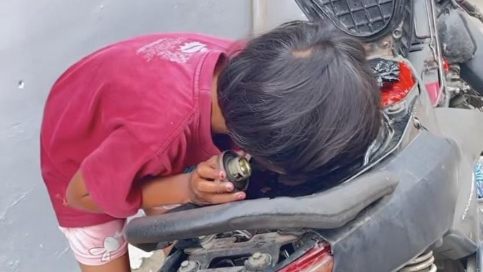 Bocah di Sukabumi membuka jok motor demi menghirup bensin.