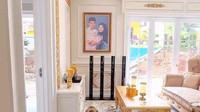Pintu dibuka langsung masuk ruang tamu terlihat ada bingkai foto Ustaz Riza Muhammad yang tengah menggendong anak dengan Indri Giana. Ini dia ruang tamunya serba emas. Sebenarnya aku suka yang minimalis, sukanya gak terlalu banyak barang, tapi suami suka banyak barang, karena kan donaturnya suami, jadi harus ada andil dia juga di sini, ujar Indri dilihat di YouTube Insertlive, Senin (6/7/2026). (Foto: dok Instagram _indrigiana_)