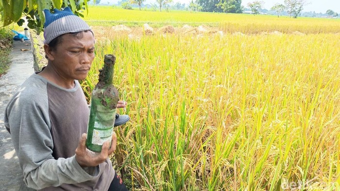 Petani di Jalan Lingkar Utara Kota Tasikmalaya menunjukkan botol miras yang banyak ditemukan di sawah mereka.