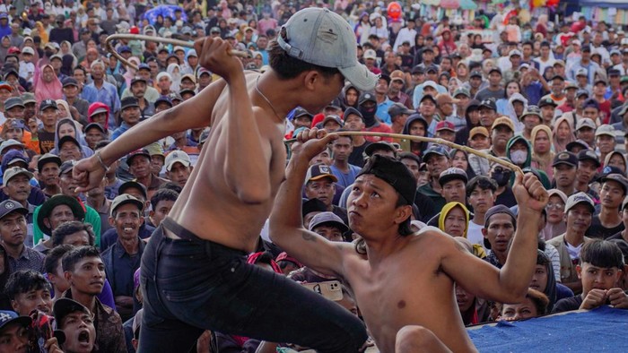 Dua warga bergantian saling menyabet menggunakan rotan saat tradisi Ojung di Desa Nguter, Kecamatan Pasirian, Lumajang, Jawa Timur, Selasa (7/7/2026). Tradisi Ojung yang digelar setiap tahun dalam rangka selamatan desa pada bulan Suro penanggalan Jawa tersebut menjadi upaya masyarakat untuk melestarikan warisan budaya sekaligus memperkuat kebersamaan warga. ANTARA FOTO/Irfan Sumanjaya