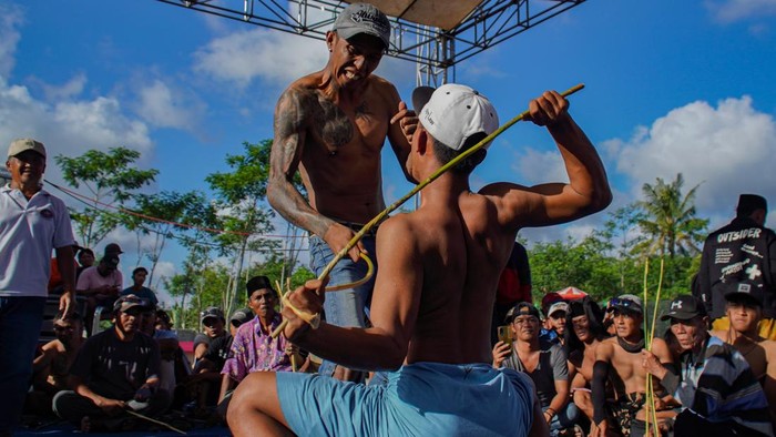 Dua warga bergantian saling menyabet menggunakan rotan saat tradisi Ojung di Desa Nguter, Kecamatan Pasirian, Lumajang, Jawa Timur, Selasa (7/7/2026). Tradisi Ojung yang digelar setiap tahun dalam rangka selamatan desa pada bulan Suro penanggalan Jawa tersebut menjadi upaya masyarakat untuk melestarikan warisan budaya sekaligus memperkuat kebersamaan warga. ANTARA FOTO/Irfan Sumanjaya