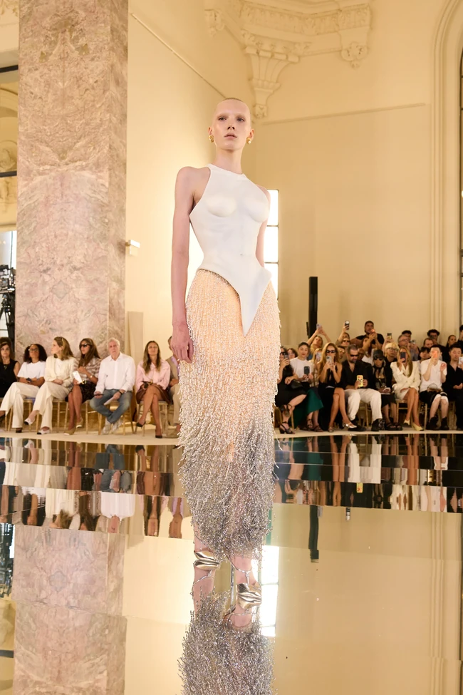Seperti dijelaskan di situs Schiaparelli, look nomor 30 ini hadir dengan bustier ‘porselen’ yang terbuat dari silikon yang dihiasi detail lacing pada bagian belakang. Bagian rok bertabur mutiara yang dibordir, lalu dilukis dengan teknik sfumato yang menciptakan efek gradasi. (Foto: Dok. Schiaparelli)