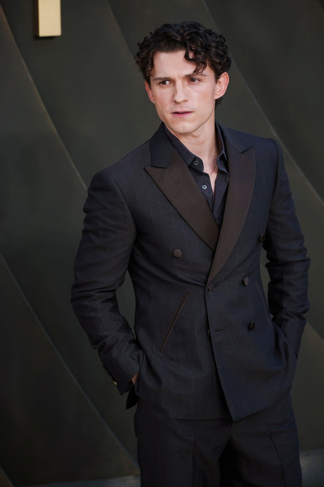 Suami Zendaya, Tom Holland, yang juga menjadi lawan mainnya, memberikan pernyataan gaya tersendiri. Ia memakai setelan coklat Gieves & Hawkes yang terbuat dari material jacquard khusus dengan detail motif kode Morse yang berbunyi ‘The Odyssey’. (Foto: REUTERS/Isabel Infantes)
