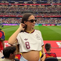 Rosa Pereira, istri dari gelandang Spanyol Fabián Ruiz, yang tengah hamil anak pertama mereka, bergaya memakai jersey Spanyol yang dibuat menjadi crop top sehingga memamerkan perutnya. Rosa berpose dengan baby bump dengan latar belakang Dallas Stadium tempat pertandingan Spanyol versus Portugal. Foto: Dok. Instagram