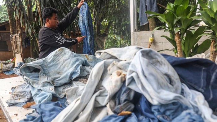 Perajin menunjukkan tas slempang dan pouch dari limbah kain jeans di rumah produksi Waste For Reuse, Bantargebang, Kota Bekasi, Jawa Barat, Rabu (8/7/2026). Rumah produksi yang mengolah limbah tekstil berupa jeans bekas menjadi tas, rompi, topi, dan gantungan kunci tersebut memproduksi sekitar 400 produk per bulan yang dipasarkan secara daring dan diekspor ke Inggris, Kanada, serta Jepang dengan harga berkisar Rp80 ribu hingga Rp450 ribu per produk sebagai upaya mengurangi limbah tekstil di kawasan sekitar TPST Bantargebang. ANTARA FOTO/Darryl Ramadhan/wsj.