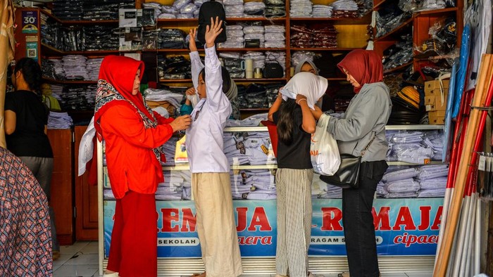 Pekerja melayani calon pembeli seragam sekolah di Pasar Kosambi, Bandung, Jawa Barat, Rabu (8/7/2026). Pemilik toko seragam sekolah menyatakan, jelang tahun ajaran baru 2026/2027 seragam yang dijual dari harga Rp150 ribu hingga Rp250 ribu per set tersebut mengalami peningkatan sebanyak 100 persen penjualan atau dapat terjual 150 pasang per hari dibandingkan hari biasa dan di prediksi akan terus meningkat hingga hari Minggu 12 Juli 2026. ANTARA FOTO/Raisan Al Farisi/wsj.