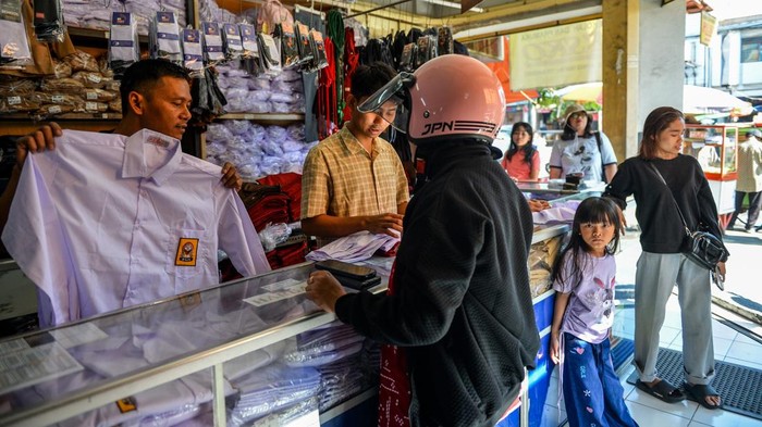 Pekerja melayani calon pembeli seragam sekolah di Pasar Kosambi, Bandung, Jawa Barat, Rabu (8/7/2026). Pemilik toko seragam sekolah menyatakan, jelang tahun ajaran baru 2026/2027 seragam yang dijual dari harga Rp150 ribu hingga Rp250 ribu per set tersebut mengalami peningkatan sebanyak 100 persen penjualan atau dapat terjual 150 pasang per hari dibandingkan hari biasa dan di prediksi akan terus meningkat hingga hari Minggu 12 Juli 2026. ANTARA FOTO/Raisan Al Farisi/wsj.