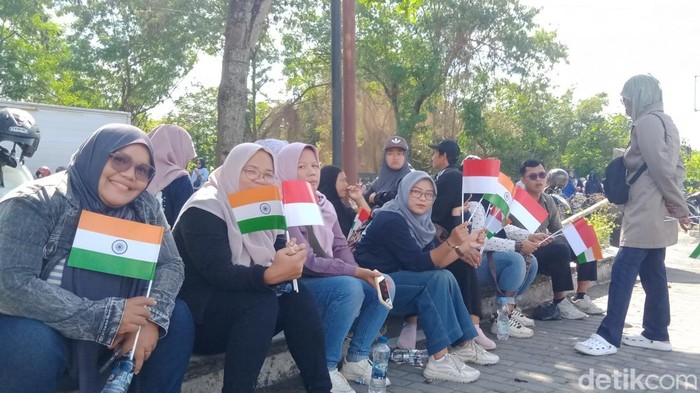 Pegawai SPPG menunggu kedatangan presiden RI Prabowo Subianto dari PM India Narendra Modi di jalan Adi Sucipto.