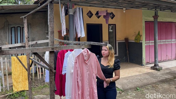 Sulis tengah merapikan jemuran di depan rumahnya di Dusun Telagasari, Desa Jambewangi, Kecamatan Sempu, Banyuwangi