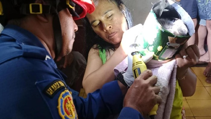 Petugas Damkar berusaha mengevakuasi kaleng biskuit yang nyangkut di kepala balita.