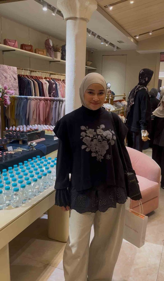 Aryani Fitriana tampil dalam balutan hijab clean look serba hitam yang berpadu serasi dengan knit vest berbahan rajut rayon premium. Rompi hitam berkerah tinggi hadir dengan detail bordir floral di bagian depan serta aksen tali pita di sisi samping. Foto: Dok. Gresnia/Wolipop.