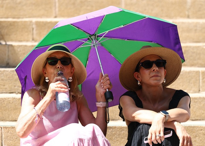 Teriknya cuaca musim panas tak menyurutkan antusiasme para penonton yang memadati kawasan The Hill di Wimbledon. Berbekal payung untuk melindungi diri dari sengatan matahari, ribuan pengunjung tetap bertahan menyaksikan pertandingan melalui layar raksasa yang disediakan di area tersebut. REUTERS/Toby Melville