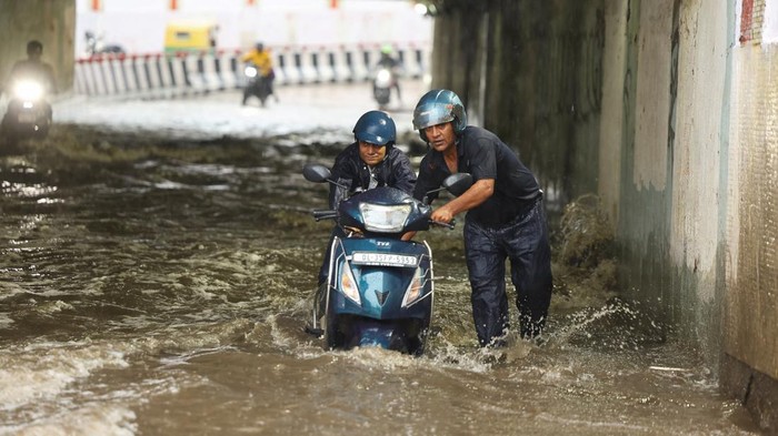 Men push a bike through a flooded road during heavy rains in New Delhi, India, July 9, 2026. REUTERS/Anushree Fadnavis