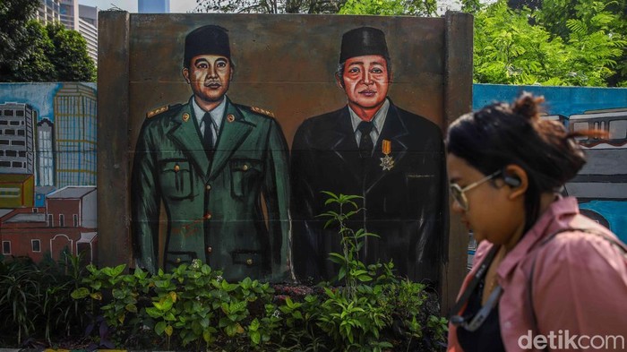 Sejumlah warga melintas di depan mural bertema Jakarta di kawasan Setiabudi, Jakarta Selatan, Kamis (9/7/2026). Deretan mural tersebut menghadirkan beragam ilustrasi yang menggambarkan perjalanan sejarah, budaya, hingga kehidupan masyarakat ibu kota dalam balutan warna-warna cerah menyambut HUT ke-500 Jakarta.