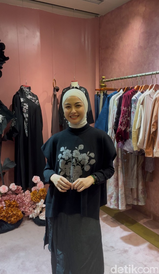 Revalina S Temat tampil dengan gaya hijab clean berwarna putih bersih yang diikat rapi ke belakang leher untuk menonjolkan detail pakaiannya. Pilihan hijab kontras tersebut berpadu sempurna dengan knit vest hitam bermotif floral, menciptakan tampilan monokrom yan elegan. Foto: Dok. Gresnia/Wolipop.