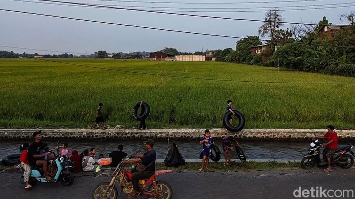 Sejumlah anak bermain air di saluran irigasi Telukjambe Barat, Karawang, Rabu (8/7/2026).