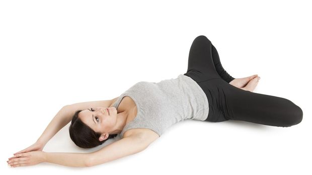 Increased whole-body view of a lying on the back young woman in yoga position 