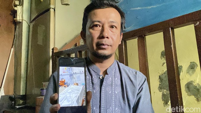 Erwin saat menunjukkan foto istrinya yang sakit tumor otak di Arab Saudi
