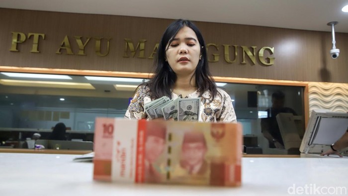 Seorang pegawai memperlihatkan mata uang Dolar Amerika Serikat (AS) dan Rupiah di money changer PT Ayu Masagung, Jakarta, Jumat (10/7/2026). Nilai tukar Dolar AS yang masih bertahan di kisaran Rp18.000 per dolar menjadi cerminan bahwa mata uang Negeri Paman Sam masih menunjukkan dominasinya terhadap rupiah.