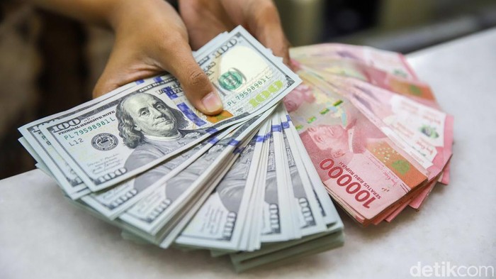 Seorang pegawai memperlihatkan mata uang Dolar Amerika Serikat (AS) dan Rupiah di money changer PT Ayu Masagung, Jakarta, Jumat (10/7/2026). Nilai tukar Dolar AS yang masih bertahan di kisaran Rp18.000 per dolar menjadi cerminan bahwa mata uang Neger