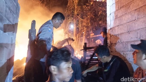 Warga dibantu polisi berupaya memadamkan api yang membakar rumah Hadijah (65) pada Jumat (10/7/2026) dini hari.