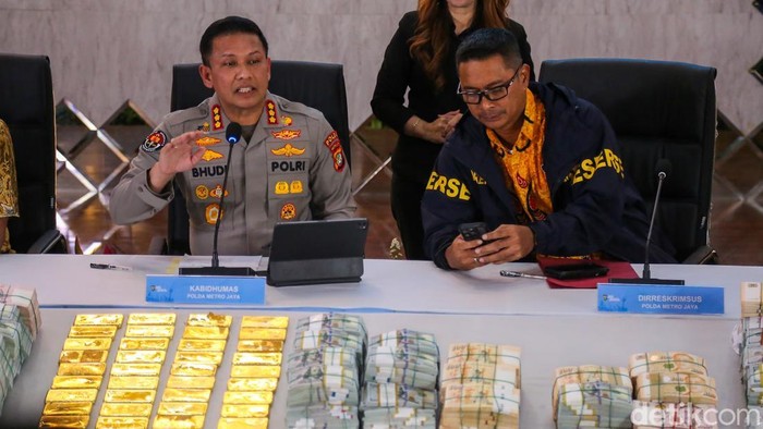 Tumpukan emas batangan dan uang asing bernilai fantastis menjadi pusat perhatian dalam konferensi pers yang digelar Polda Metro Jaya di Gedung Promoter, Jakarta, Jumat (10/7/2026). Barang bukti hasil penggeledahan di sejumlah lokasi itu dipamerkan di