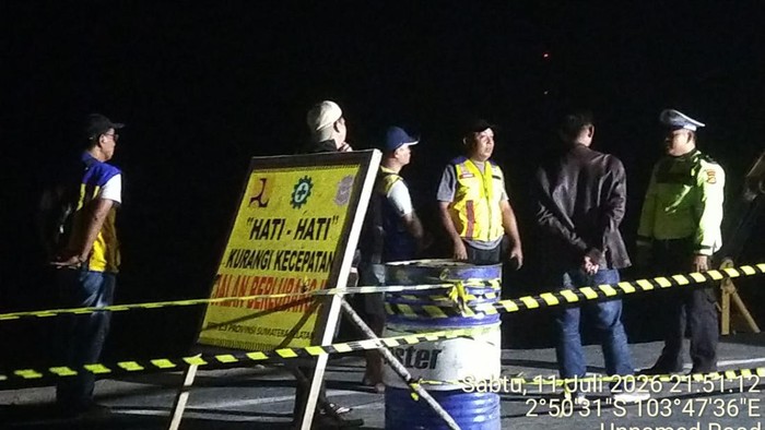 Anggota Polres Musi Banyuasin berjaga di lokasi jalan yang amblas