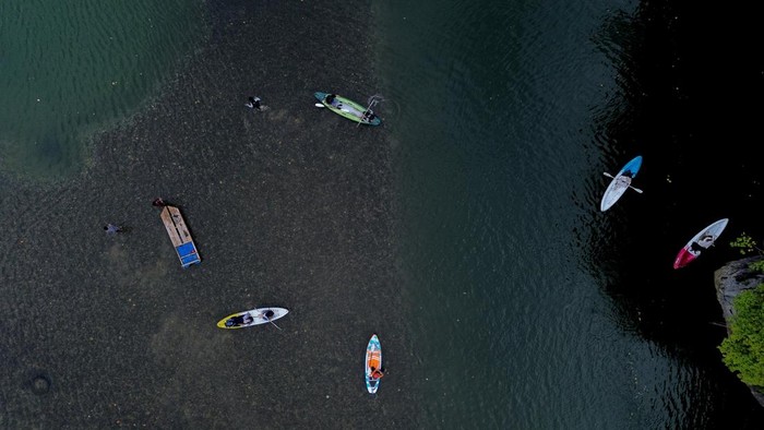 Sejumlah wisatawan bersiap menaiki papan selancar dayung (paddle board) di Danau Lhok Gaca, Aceh Besar, Aceh, Minggu (12/7/2026). Danau berair jernih yang diapit tebing batu dan berbatasan langsung dengan laut tersebut menjadi salah satu destinasi wisata alam di Aceh Besar yang menawarkan aktivitas paddle board dengan jumlah pengguna sekitar 70 hingga 120 orang per hari saat musim liburan. ANTARAFOTO/Akramul Muslim/bar