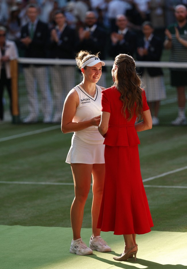 Seperti tradisi setiap tahun sejak menjadi patron Wimbledon pada 2016, Kate juga mengenakan pin berbentuk pita hijau dan ungu di bagian dada. Aksesori kecil tersebut merupakan lambang resmi All England Club sekaligus penanda perannya sebagai patron turnamen Wimbledon. Pada partai final, Kate juga memiliki tugas menyerahkan trofi kepada juara dan runner-up. Foto: REUTERS/Toby Melville