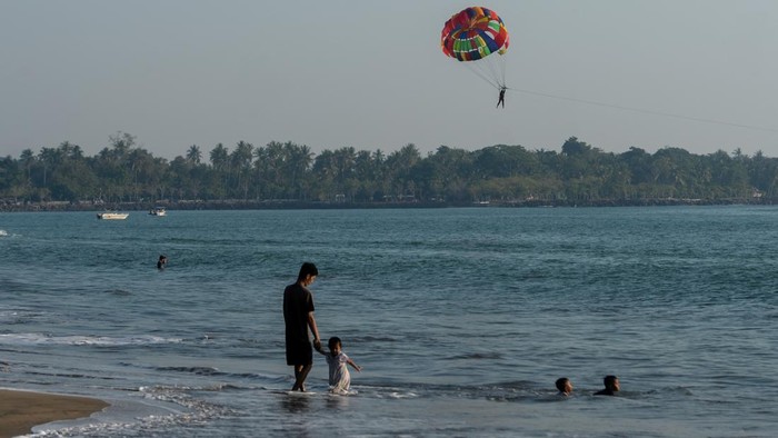 Wisatawan bermain air di kawasan wisata Pantai Anyer, Kabupaten Serang, Banten, Minggu (12/7/2026). Pemkab Serang dan PVMBG menjamin kawasan wisata Pantai Anyer dan Cinangka aman dikunjungi oleh wisatawan karena berjarak 42 km atau berada di luar radius bahaya Gunung Anak Krakatau yang berstatus Siaga (Level III). ANTARA FOTO/Muhammad Bagus Khoirunas