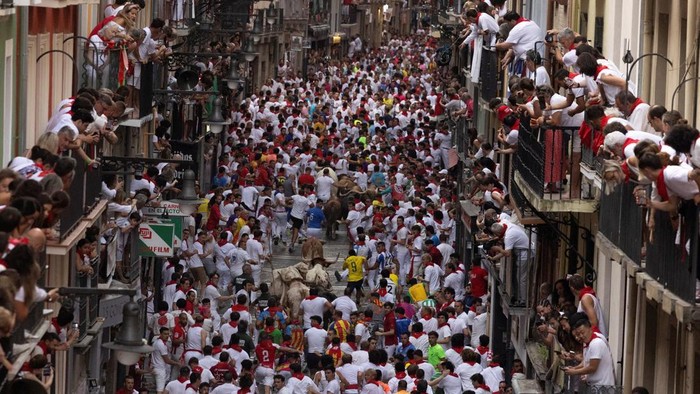 Runners sprint alongside Miura bulls during the Running of the Bulls at San Fermin festival, where each morning for eight days hundreds of festival-goers share an 875-meter (0.54-mile) course with six fighting bulls leaving their corral and heading for the bull ring, in Pamplona, Spain, July 13, 2026. REUTERS/Vincent West