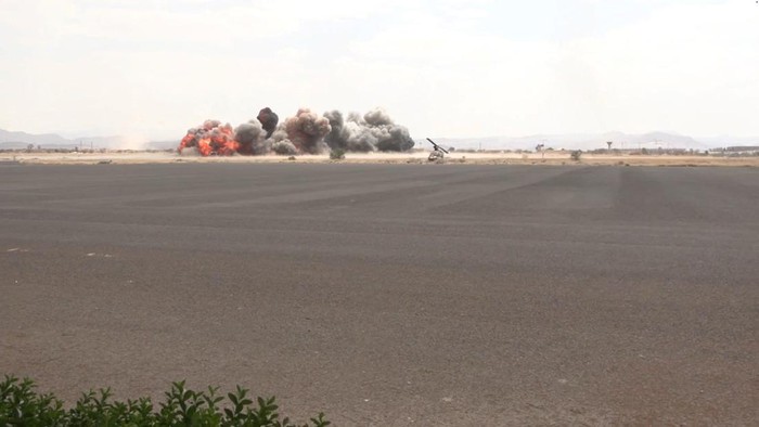 Kepulan asap menjulang ke udara saat serangan menghantam Bandara Internasional Sanaa di Yaman pada Senin (13/7) waktu setempat. Houthi menuduh Saudi mendalangi serangan tersebut. (AL MASIRAH/Handout via REUTERS)
