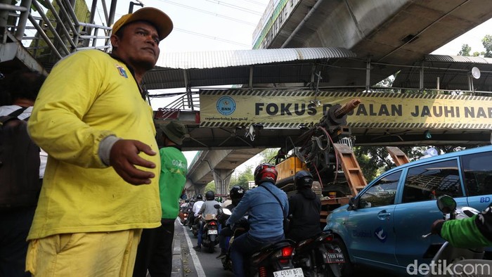 Petugas mengamankan lokasi Jembatan Penyeberangan Orang (JPO) di Jalan Kapten Tendean, Jakarta Selatan, Selasa (14/7/2026). JPO mengalami kerusakan setelah ditabrak truk pengangkut alat berat.