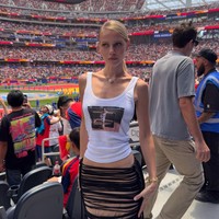 Salah satu penampilan paling kreatif datang dari Laura Schmitt. Ia mengubah foto masa kecil kekasihnya, Gelandang Spanyol Dani Olmo, menjadi elemen utama pada busananya. Potret nostalgia tersebut menjadi pusat perhatian yang dipadukan dengan distressed skirt serta aksesori bernuansa elegan. Hasilnya bukan sekadar outfit untuk mendukung pasangan di stadion, melainkan sebuah medium bercerita yang personal. Penampilannya dianggap sebagai salah satu konsep fashion paling orisinal sepanjang Piala Dunia 2026. (Foto: Instagram)
