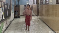 Namun, genangan air tak menghentikan aktivitas warga. Anak-anak tetap berangkat sekolah.