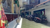 Halaman SD Karya Putra terendam banjir rob. Siswa kelas VI yang ruang belajarnya terdampak tetap mengikuti pelajaran.