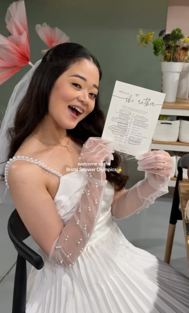 Cindy tampil anggun dalam balutan dress putih sleeveless. Dress tersebut berhiaskan taburan manik-manik mutiara pada bagian tali lengannya. Ia juga melengkapi penampilannya dengan sarung tangan transparan yang juga dihiasi dengan mutiara. Foto: Instagram/@giselacindy12