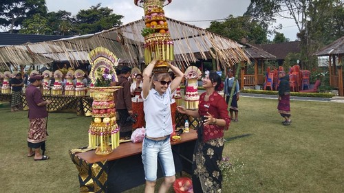 Wisatawan mancanegara mencoba menjunjung gebogan di Festival Budaya DTW Ulun Danu Beratan, Kecamatan Baturiti, Tabanan, Rabu (15/7/2026). (Krisna Pradipta/detikBali)