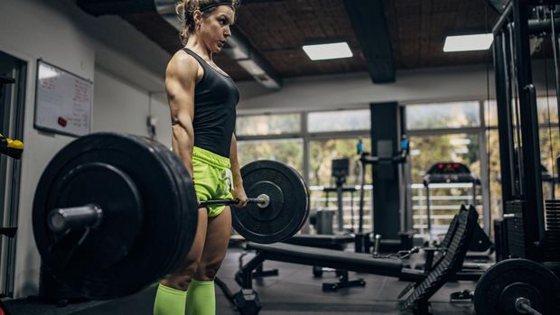 One woman, strong woman exercising with weights in gym.
