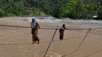 Guru dan siswa di kawasan itu terpaksa menggunakan jembatan tali baja untuk berangkat dan pulang sekolah. Jalur darurat itu menghubungkan Dusun Sarah Sare dan Dusun Durian untuk aktivitas belajar setiap hari. Foto: ANTARA FOTO/SYIFA YULINNAS