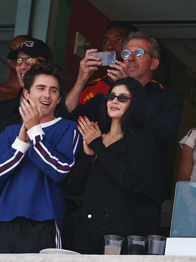 Tak hanya kompak, keduanya juga tampil serasi dengan gaya kasual. Kylie memilih busana serba hitam yang terdiri dari atasan lengan panjang, celana cropped hitam, dan sandal kitten heels senada. Sementara itu, Timothée mengenakan setelan Adidas berupa kaus lengan panjang biru, celana training hitam, dan sneakers. Foto: AFP/FRANCK FIFE