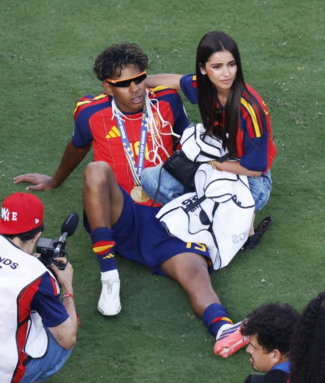 Lamine bergaya dengan kacamata hitam bernuansa futurstis. Ines, yang memakai jersey merah Spanyol dengan nomor punggung Lamine (19), setia sembari merangkul pria 19 tahun itu. (Foto: REUTERS/Brian Snyder)