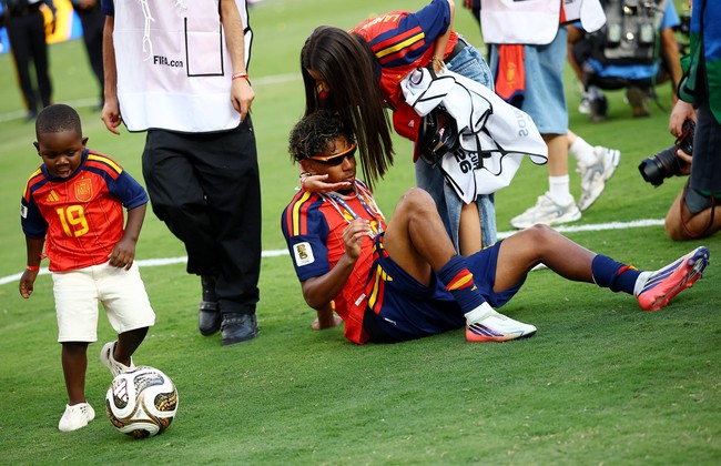 Ines memberikan pelukan kepada Lamine yang larut dalam sukacita atas kemenangan timnas Spanyol. Adik Lamine, Keyne Yamal, juga turun lapangan untuk mengucapkan selamat. (Foto: REUTERS/Agustin Marcarian)