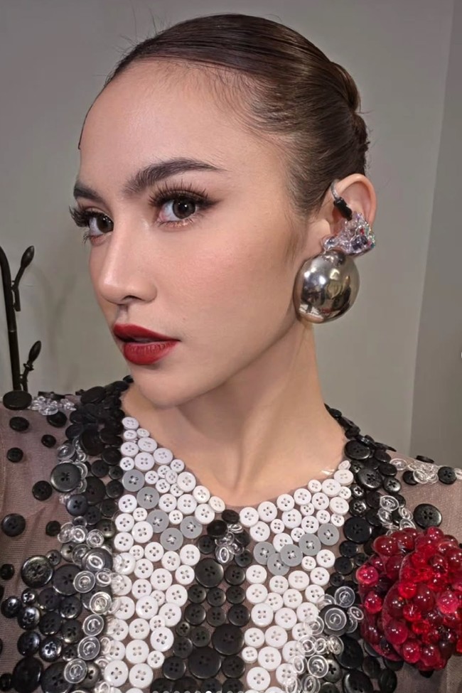 Makeup Mahalini mengusung tampilan glamor. Kompleksi wajah dibuat flawless dengan contour yang membentuk dimensi wajah, alis terbingkai rapi, eyeliner tajam, bulu mata lentik, serta lipstik merah yang menjadi focal point penampilannya. Foto: Instagram/@mahaliniraharja